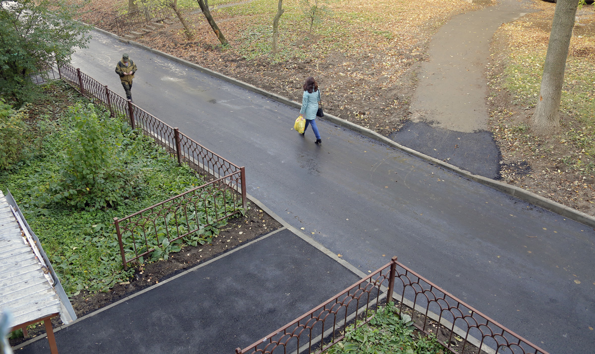 Пешеходная дорожка. Широкий тротуар. Современная улица. Люди идут по тротуару. Идет вдоль дома.